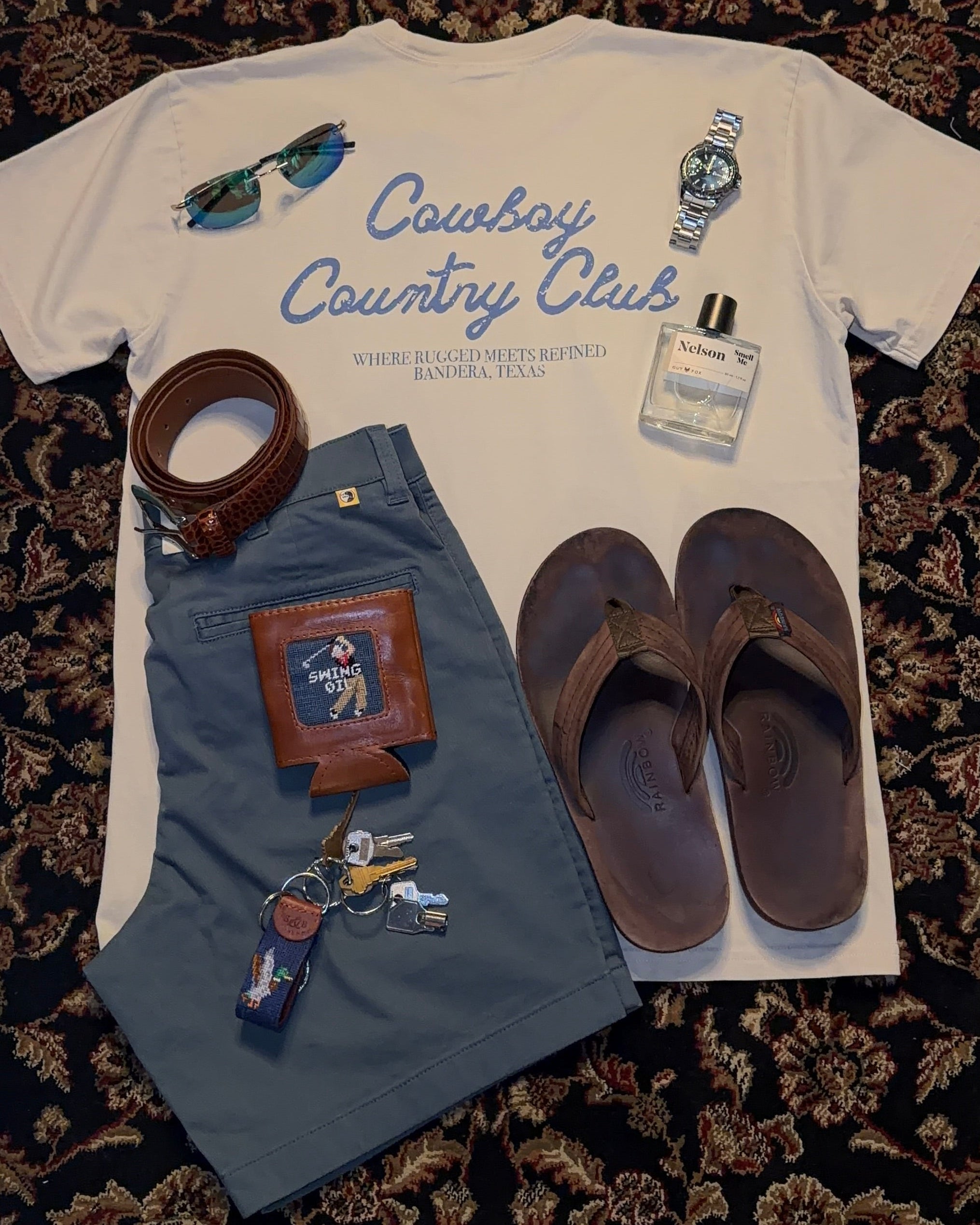 Baby outfit with t-shirt, shorts, sandals, and accessories on a patterned surface