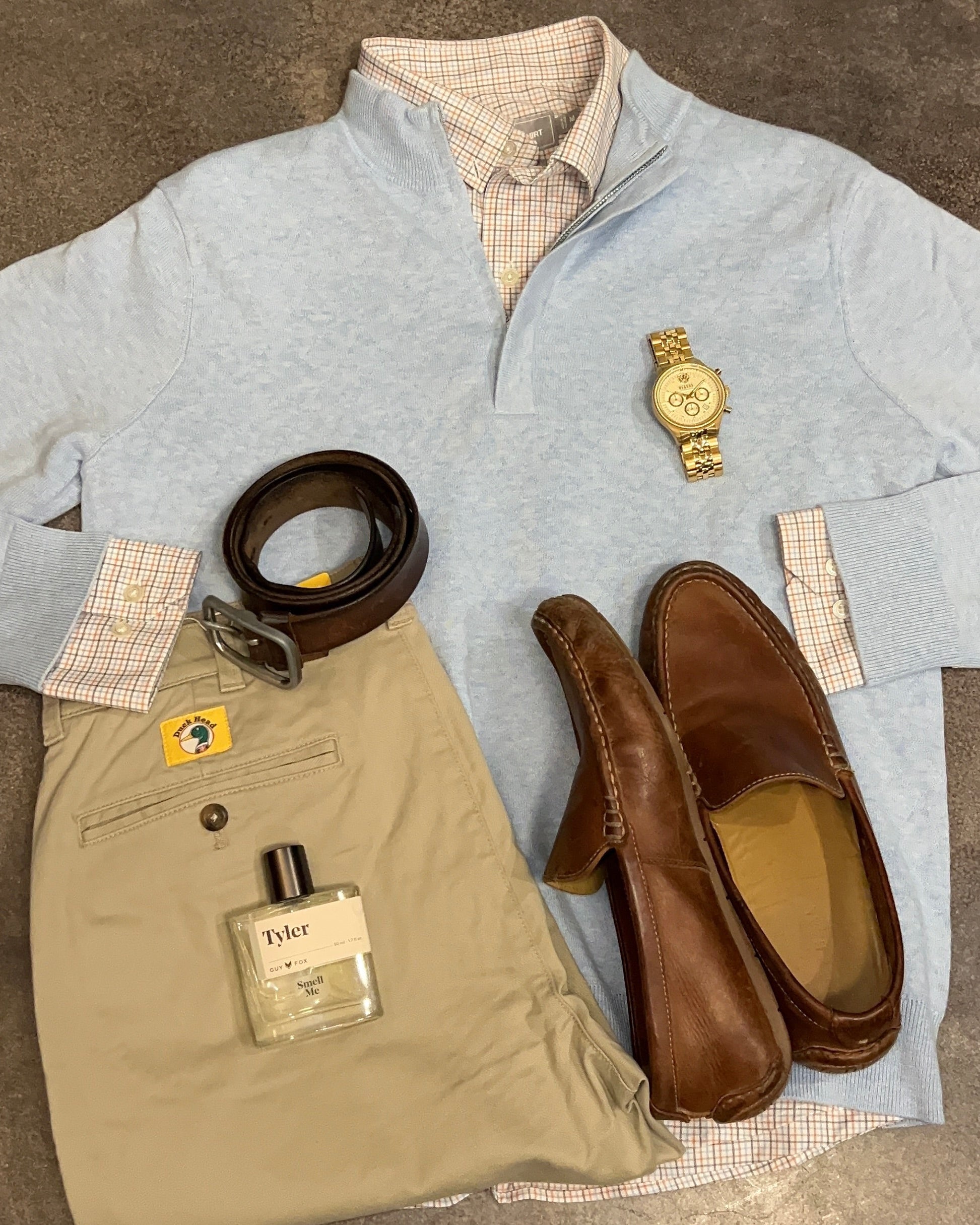 Collection of men's clothing and accessories on a textured surface