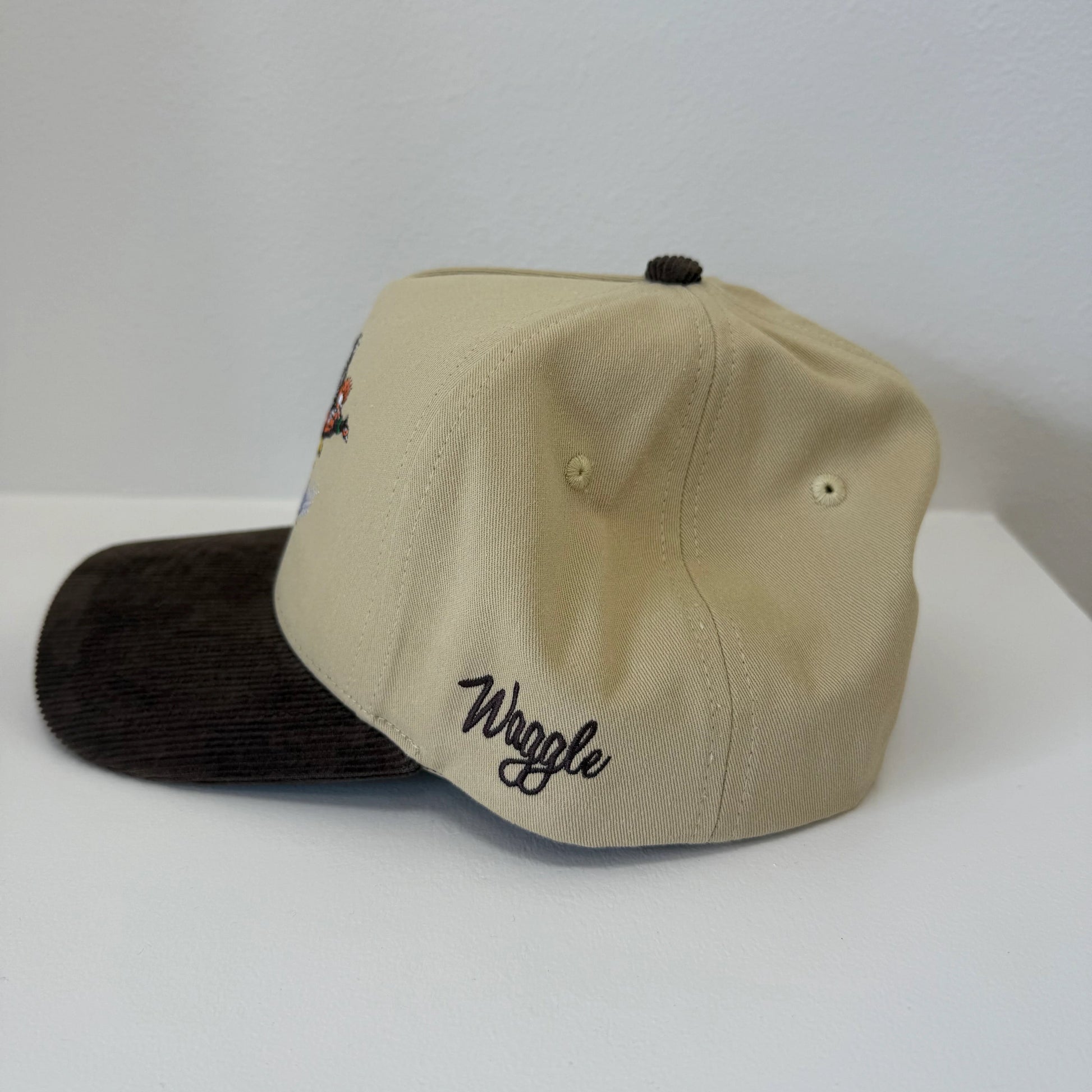 Beige cap with 'Waggle' logo on a white surface