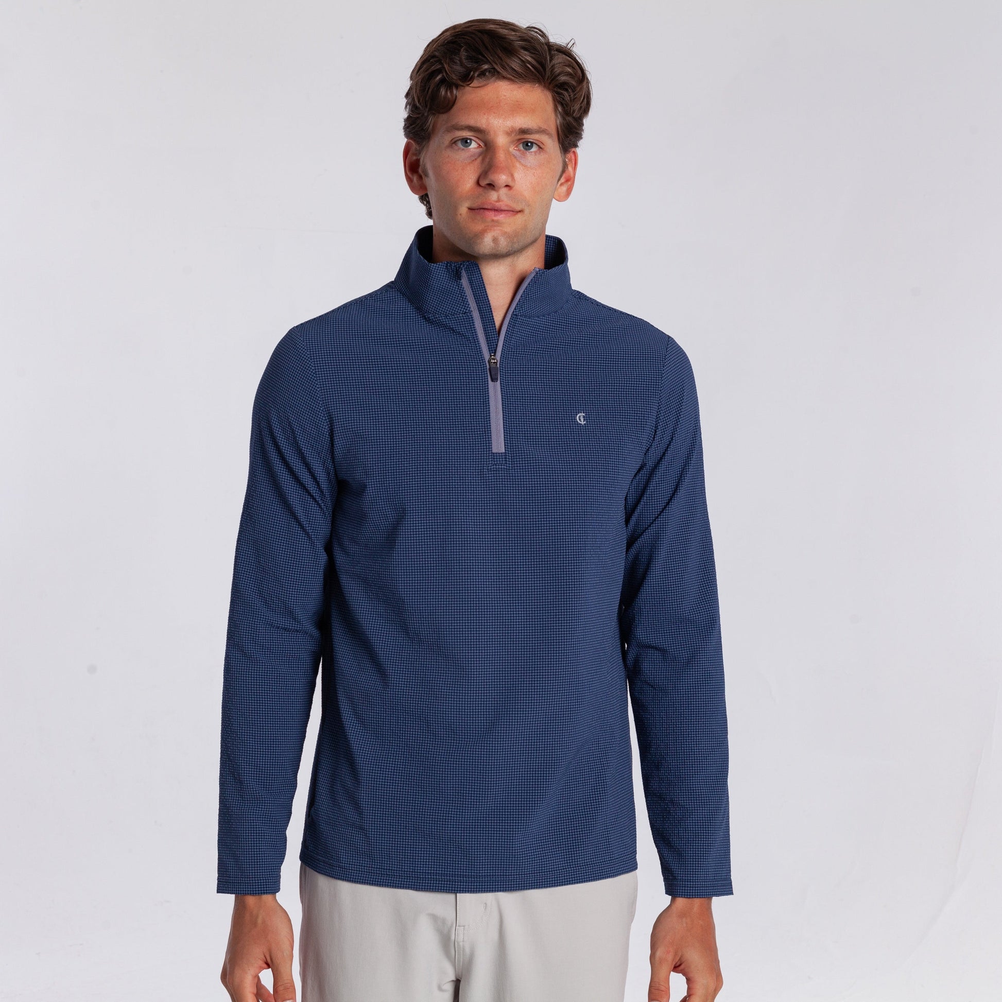 Man wearing a blue pullover with a quarter zip on a white background