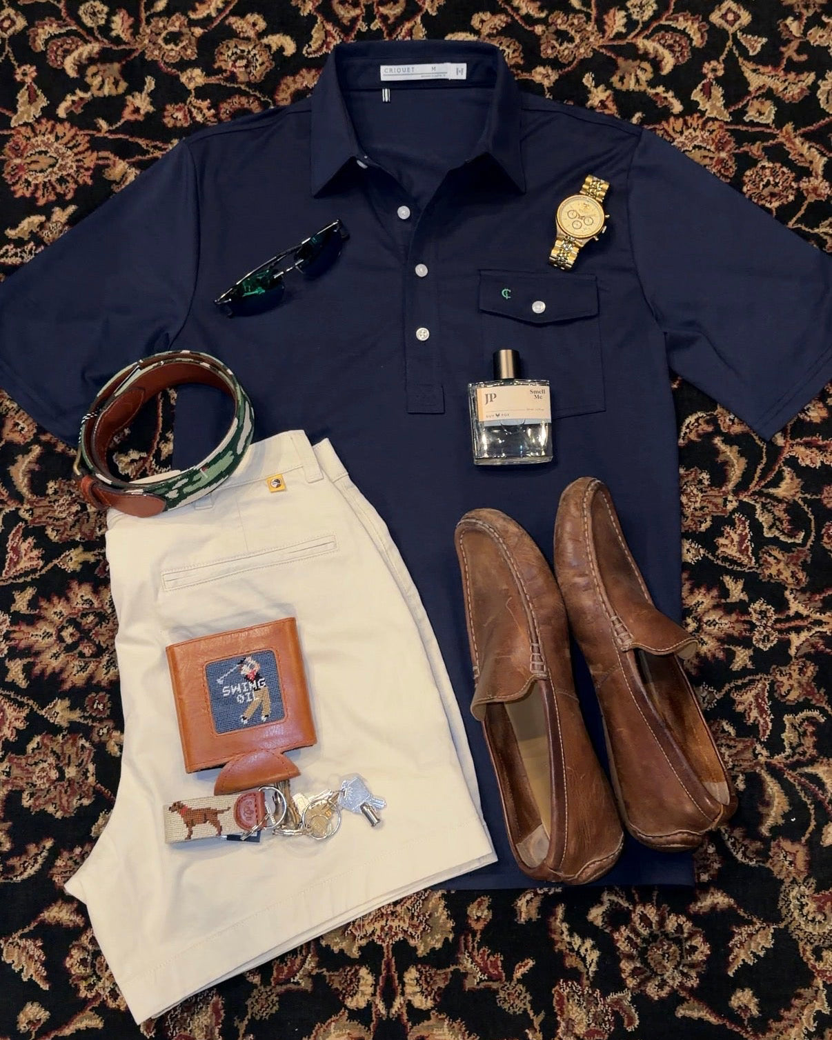 Navy shirt with accessories on a patterned rug