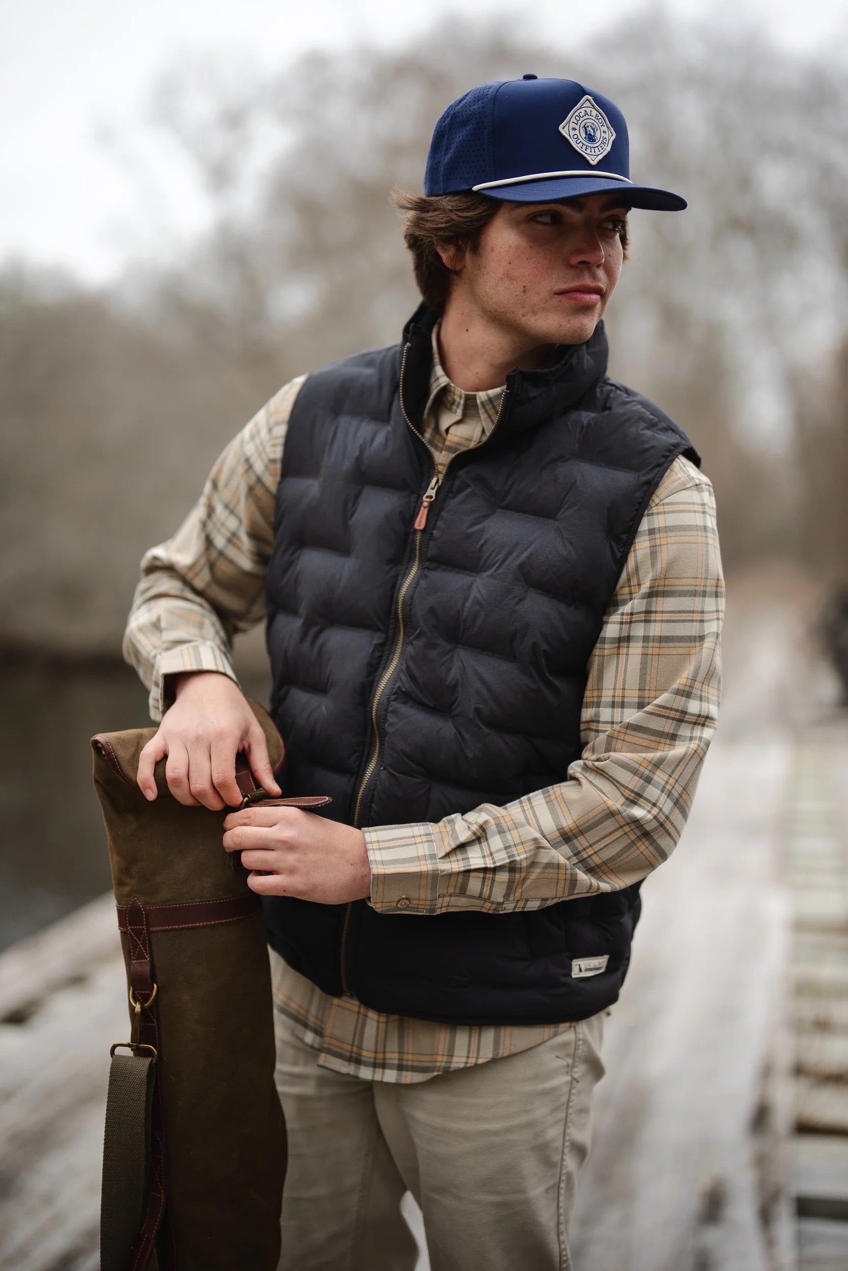 Person wearing a navy puffer vest and cap outdoors
