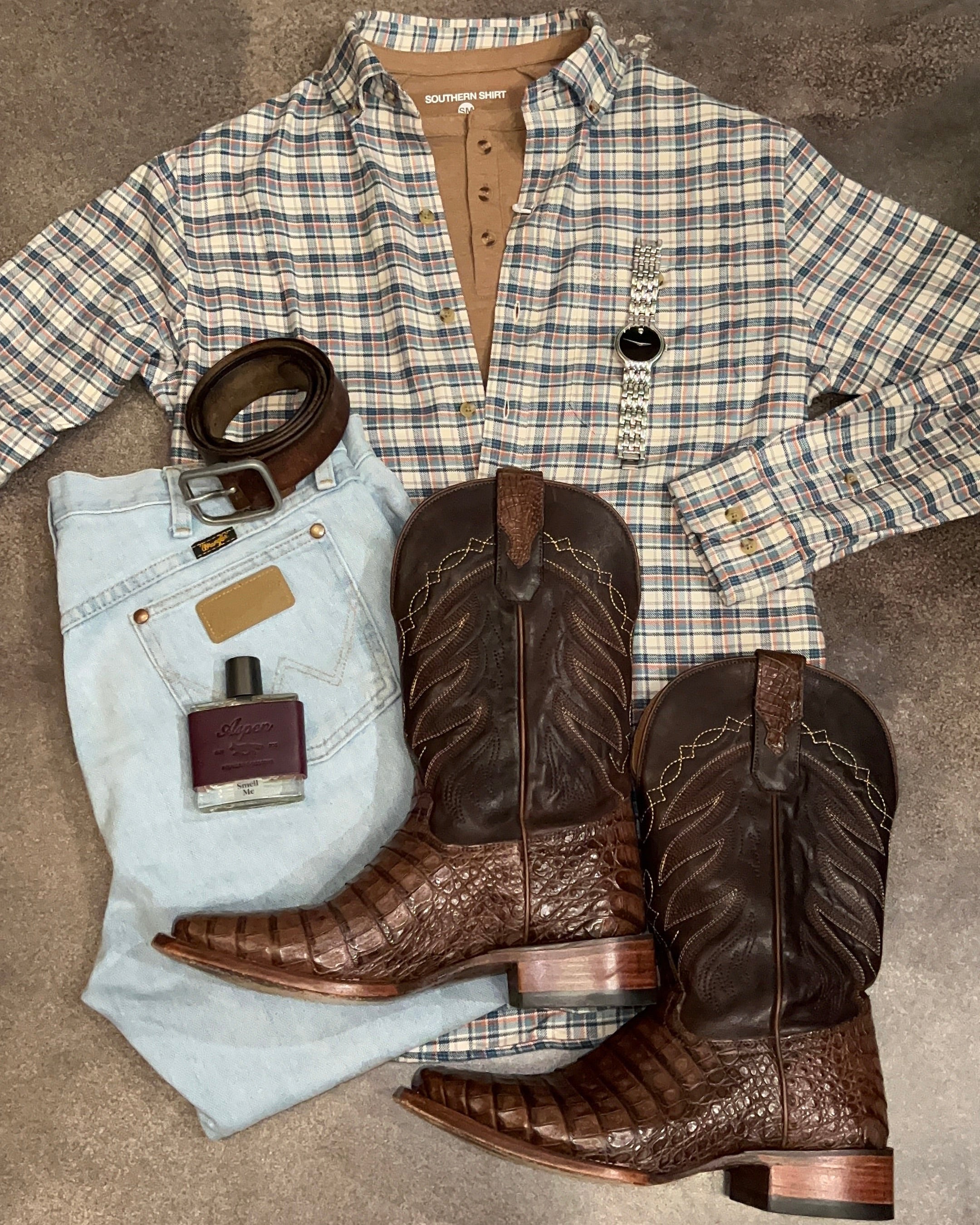Plaid jacket, jeans, and brown cowboy boots on a textured surface