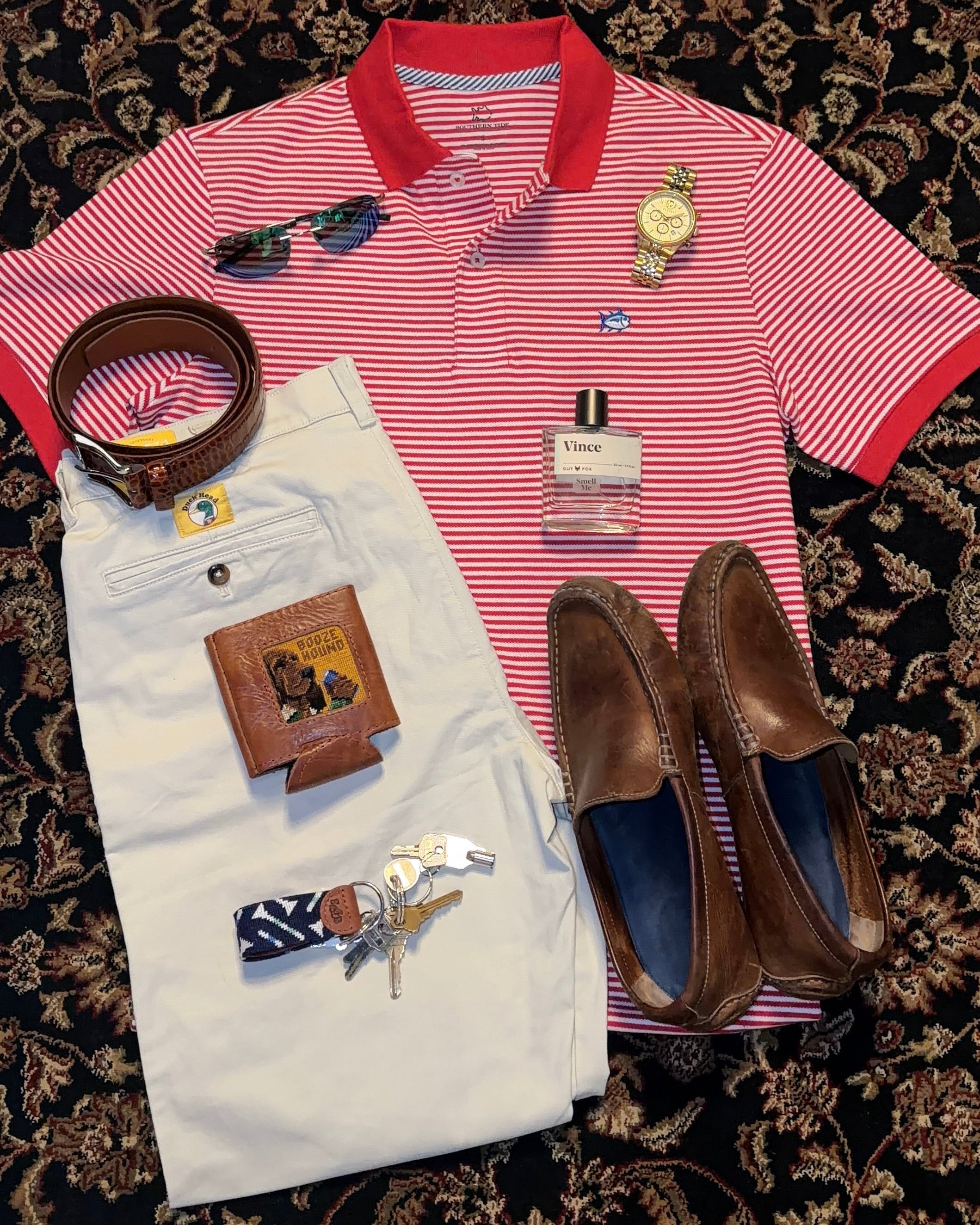 Red and white striped polo shirt with accessories on a patterned surface